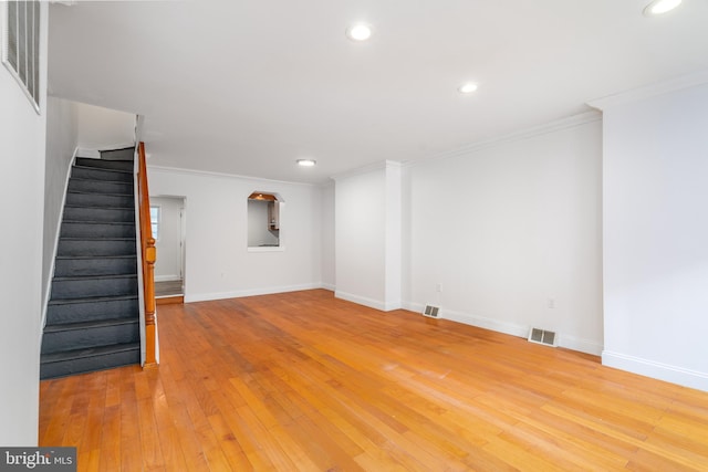 unfurnished living room with stairs, baseboards, crown molding, and wood finished floors