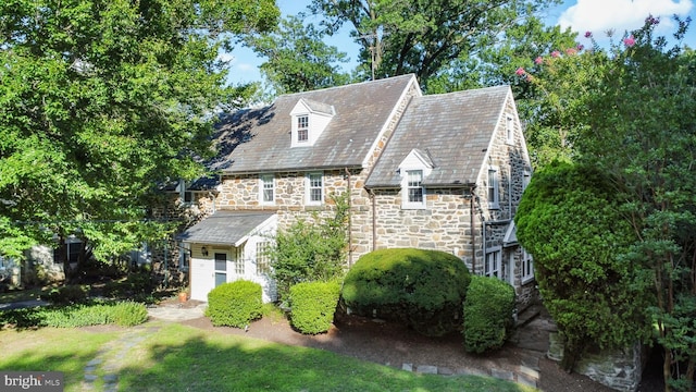 view of front facade with stone siding, a high end roof, and a front lawn