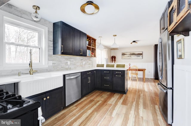 kitchen with pendant lighting, light wood finished floors, open shelves, stainless steel appliances, and light countertops