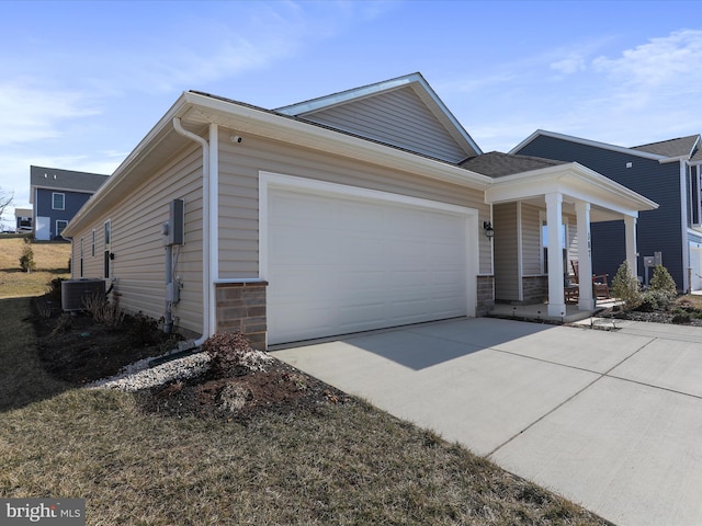 view of front facade with a porch, cooling unit, a garage, stone siding, and driveway