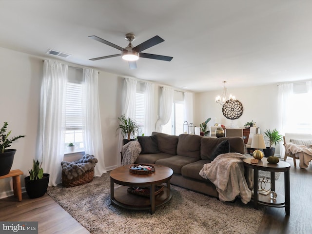 living area featuring ceiling fan with notable chandelier, visible vents, and wood finished floors