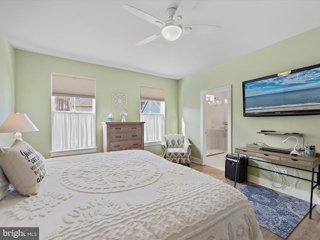 bedroom featuring baseboards, ensuite bath, a ceiling fan, and wood finished floors