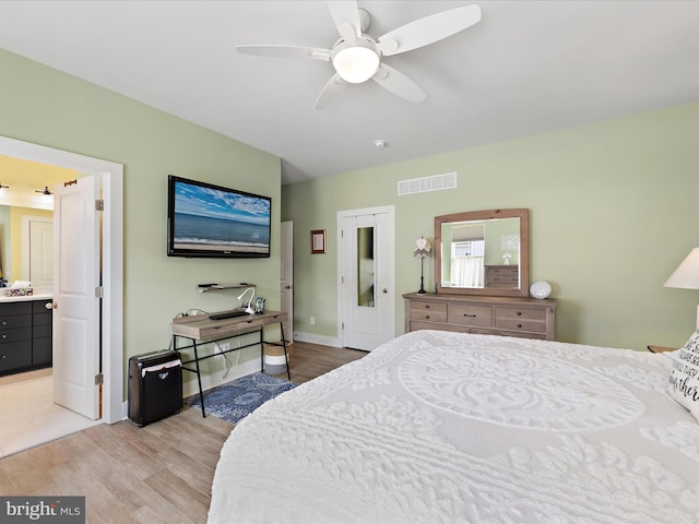 bedroom with light wood-style floors, baseboards, visible vents, and ensuite bathroom