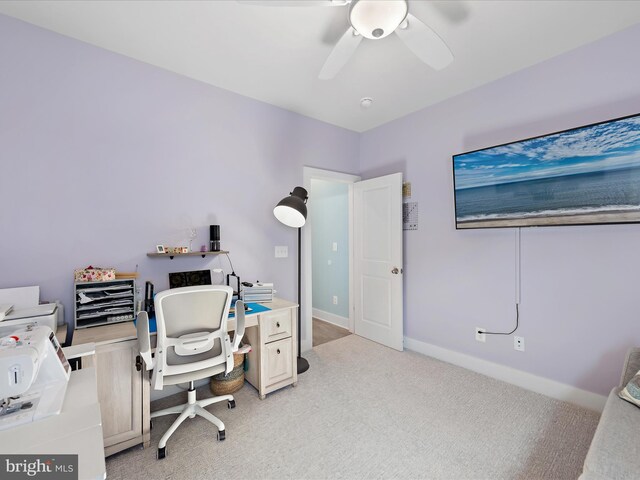 office area featuring light carpet, baseboards, and a ceiling fan