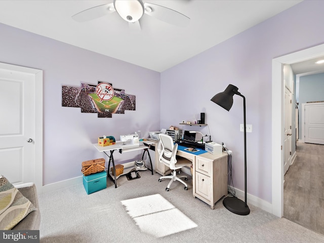 office space featuring light carpet, ceiling fan, and baseboards