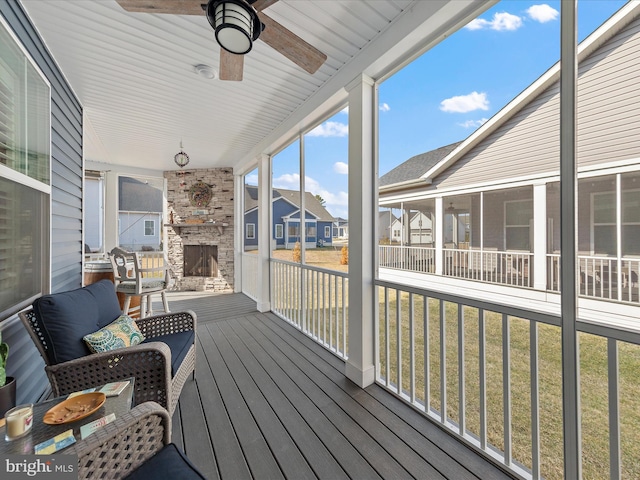 wooden deck featuring a sunroom, ceiling fan, a residential view, and a lawn