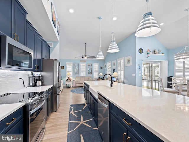 kitchen with blue cabinets, stainless steel appliances, a sink, light countertops, and light wood-type flooring