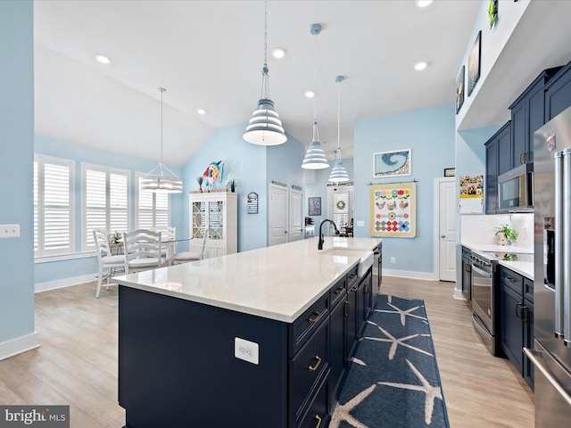 kitchen featuring a kitchen island with sink, a sink, baseboards, appliances with stainless steel finishes, and light wood-type flooring