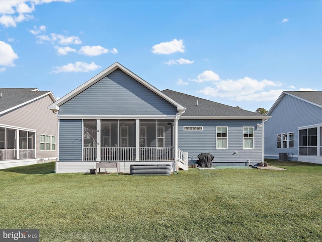 back of property with central AC unit, a lawn, a shingled roof, and a sunroom