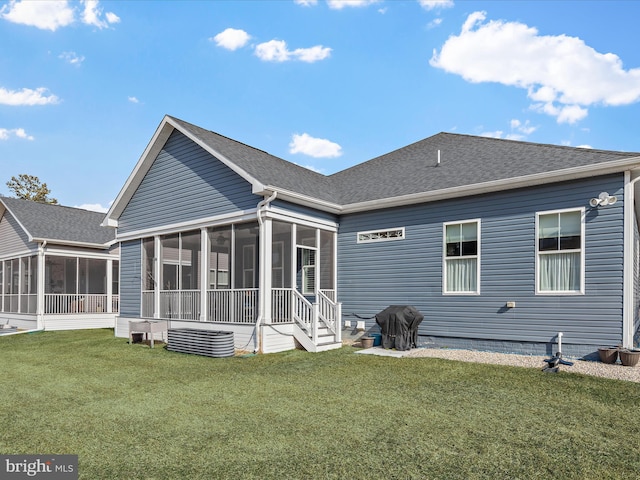 back of property with a sunroom, roof with shingles, and a lawn