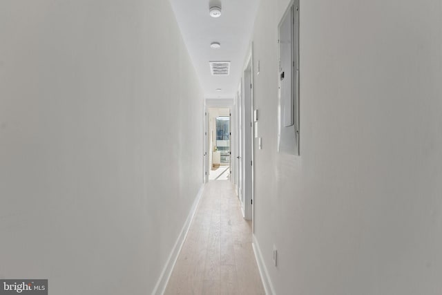 hall featuring light wood-type flooring, visible vents, and baseboards