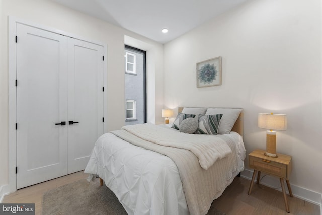 bedroom with a closet, baseboards, wood finished floors, and recessed lighting