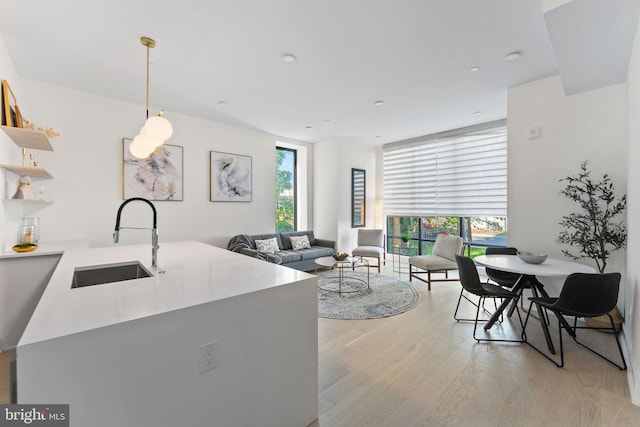 kitchen with a sink, light countertops, light wood-type flooring, open shelves, and pendant lighting