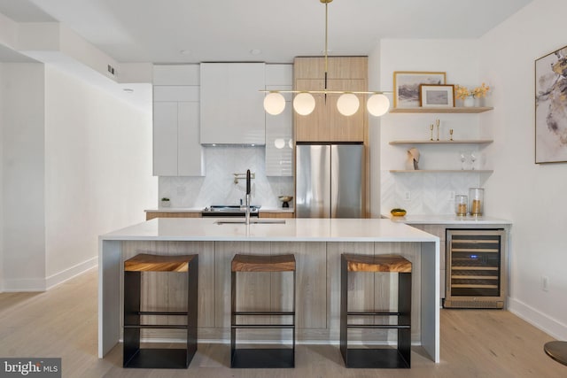 kitchen featuring beverage cooler, light countertops, freestanding refrigerator, open shelves, and modern cabinets