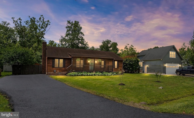 view of front of property featuring asphalt driveway, a chimney, a lawn, and an outbuilding