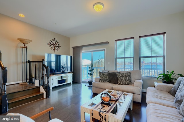 living room with a wealth of natural light, stairway, baseboards, and wood finished floors