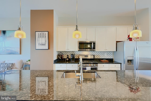 kitchen with decorative light fixtures, appliances with stainless steel finishes, white cabinetry, and tasteful backsplash