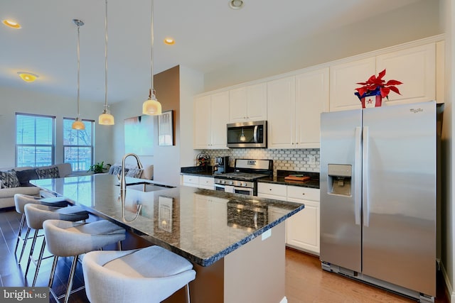 kitchen with stainless steel appliances, tasteful backsplash, a sink, and white cabinetry