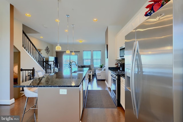 kitchen featuring a center island with sink, white cabinets, dark wood-style floors, a kitchen breakfast bar, and stainless steel appliances