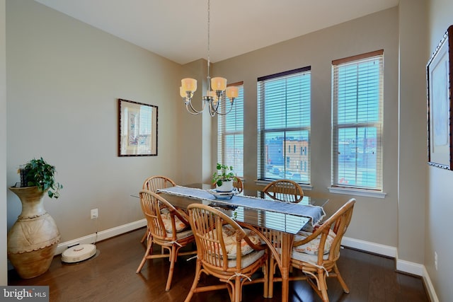 dining space featuring a chandelier, dark wood finished floors, and baseboards