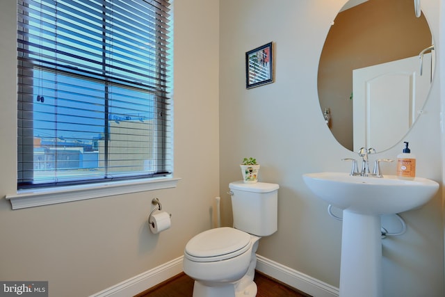 half bath with toilet, plenty of natural light, and baseboards