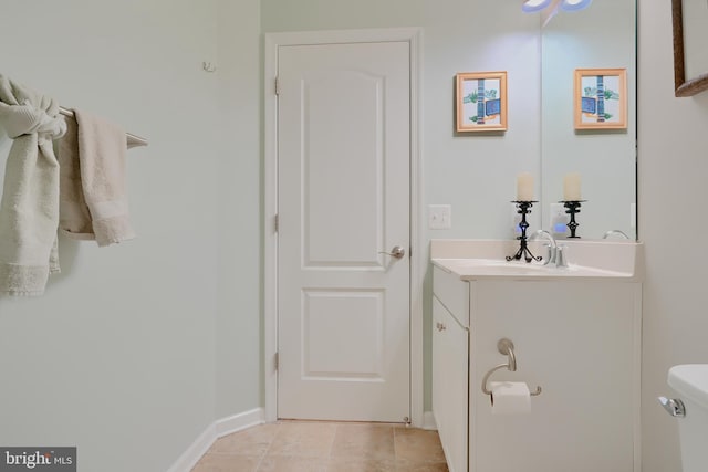 half bathroom with toilet, tile patterned flooring, baseboards, and vanity