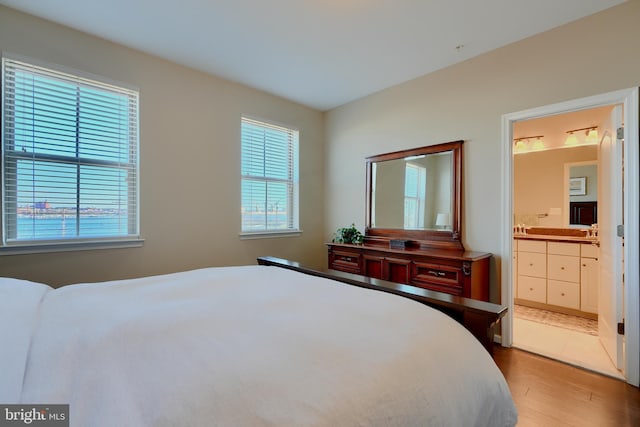 bedroom with connected bathroom and wood finished floors