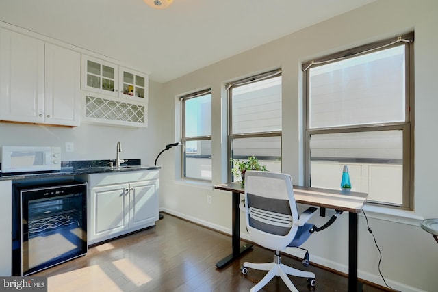 office featuring wine cooler, dark wood-style flooring, a sink, wet bar, and baseboards