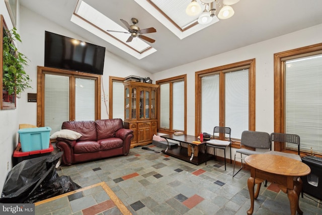 living area featuring lofted ceiling with skylight, stone finish flooring, and an inviting chandelier