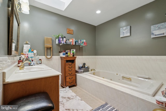 full bathroom with a jetted tub, a skylight, tile patterned floors, and vanity