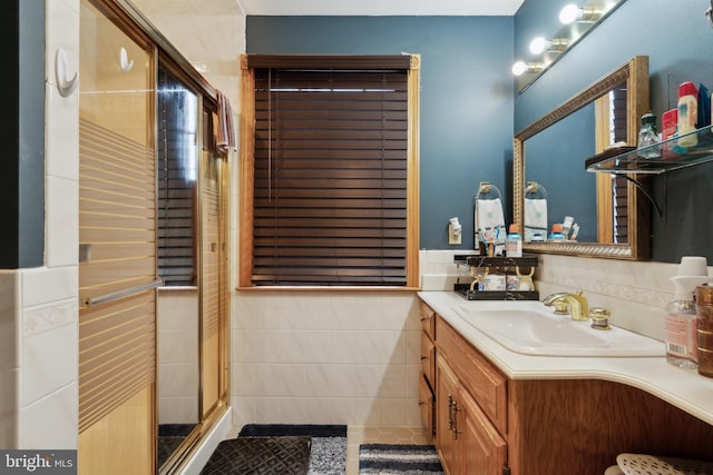 bathroom with a shower stall, tile walls, vanity, and tile patterned floors