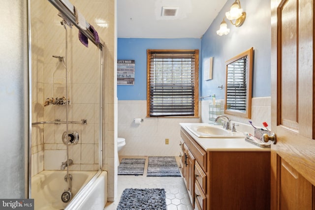 bathroom featuring toilet, shower / bath combination, vanity, visible vents, and tile walls