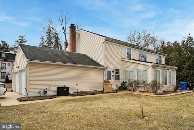 back of house featuring a garage, central AC, a yard, concrete driveway, and a chimney