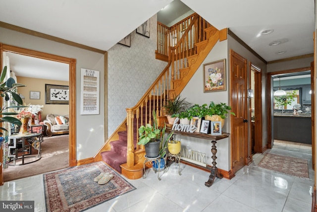 staircase featuring crown molding, an accent wall, baseboards, and wallpapered walls