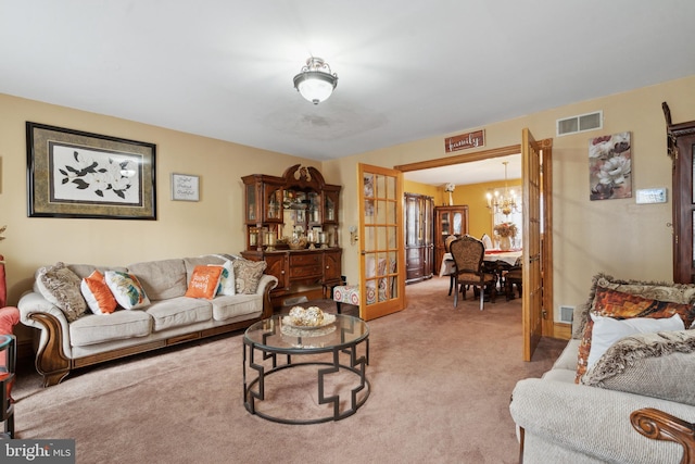 living room with visible vents, a chandelier, and light colored carpet