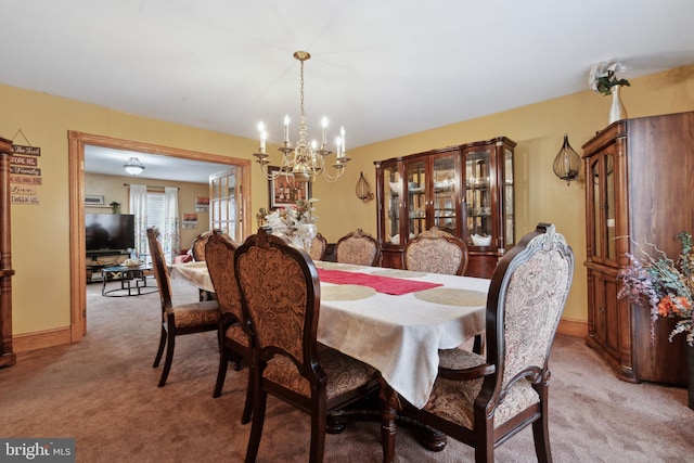 dining area featuring a chandelier, light colored carpet, and baseboards