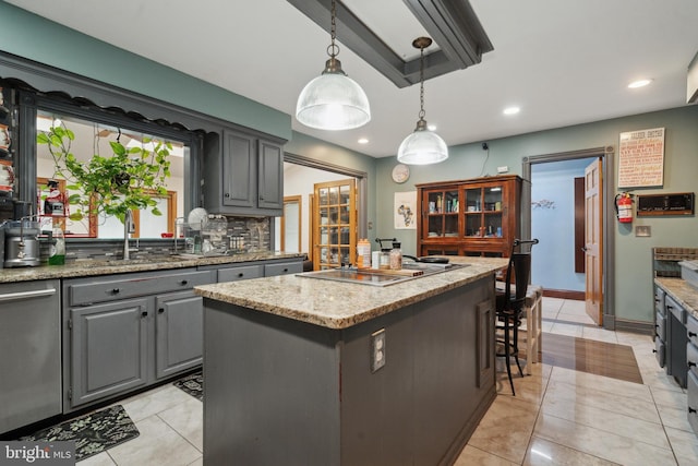 kitchen with tasteful backsplash, a kitchen island, decorative light fixtures, gray cabinetry, and a sink