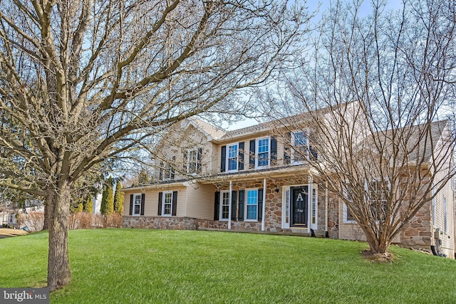 view of front facade with stone siding and a front lawn