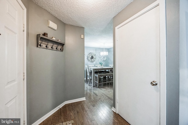 hall with a textured ceiling, baseboards, and wood finished floors