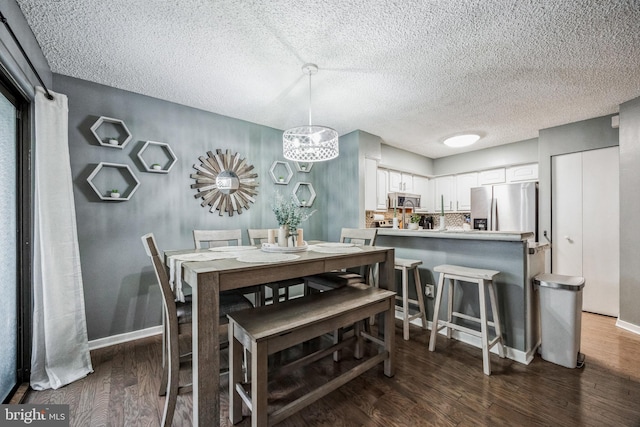 dining area with a textured ceiling, baseboards, and dark wood-style flooring