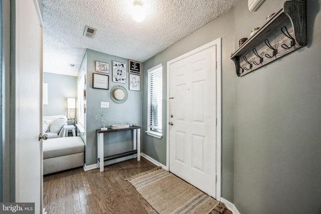 entryway with a textured ceiling, dark wood finished floors, visible vents, and baseboards