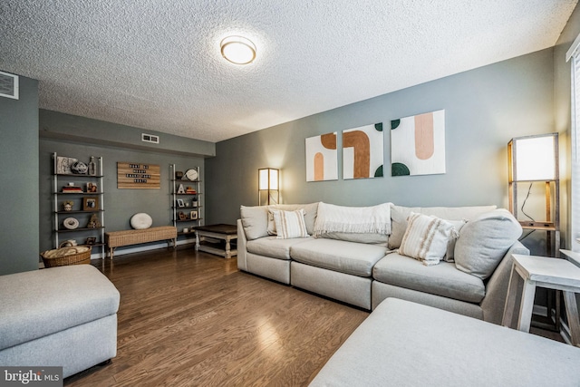 living room featuring a textured ceiling, visible vents, and dark wood-style flooring