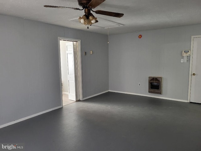 unfurnished living room with ceiling fan, concrete floors, baseboards, heating unit, and attic access