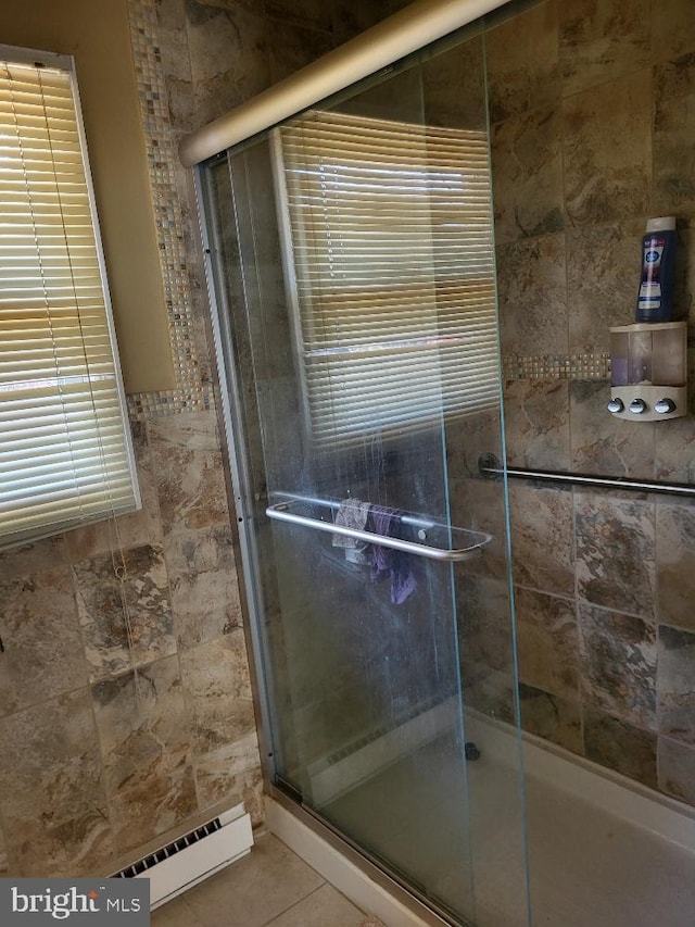 bathroom featuring baseboard heating, a tile shower, and tile patterned floors