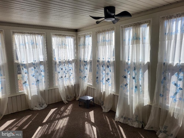 unfurnished sunroom with a ceiling fan, wood ceiling, and a healthy amount of sunlight