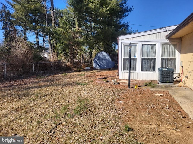 view of yard featuring fence, a storage shed, and central AC unit