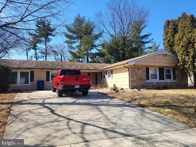 single story home with driveway and stone siding