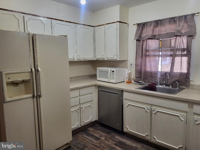 kitchen featuring dark wood-style floors, light countertops, white cabinets, a sink, and white appliances