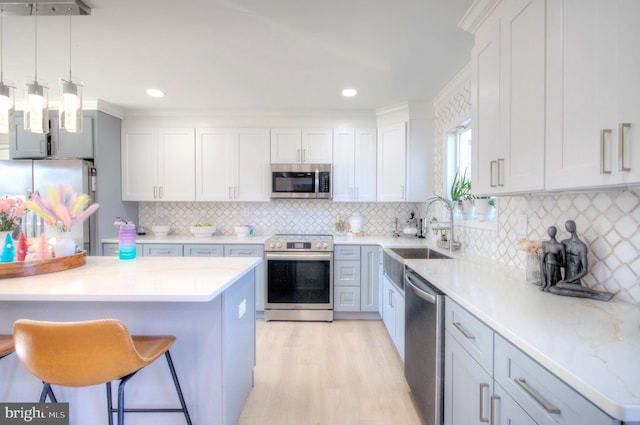 kitchen with a breakfast bar area, a sink, white cabinetry, light countertops, and appliances with stainless steel finishes