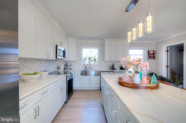 kitchen featuring white cabinets, ornamental molding, a sink, stainless steel appliances, and backsplash